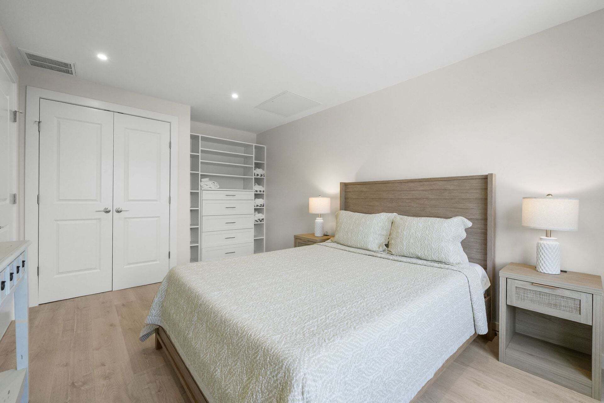 A bedroom with a bed, two bedside tables, a wardrobe, and a closet.