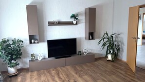 Ein modernes Wohnzimmer mit Flachbildfernseher, Holzboden und Einbauschränken.