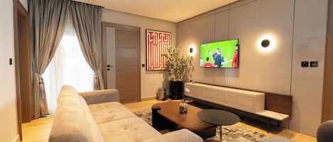 Una sala de estar moderna con un sofá, una mesa de centro y un televisor montado en la pared.