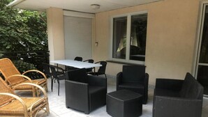 Een terras buiten met rieten meubels, een tafel en een raam.