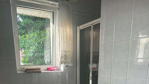Een badkamer met toilet, bidet, wastafel en een raam met uitzicht op groen.