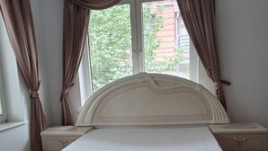 Een slaapkamer met een bed, nachtkastjes, een kroonluchter en gordijnen.