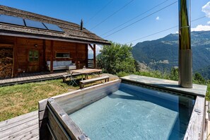 Uma cabana de madeira com piscina, um pátio e vista para as montanhas.