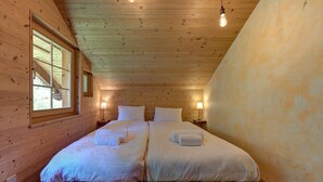 Quarto de cabana de madeira com duas camas, uma janela e uma lâmpada.