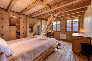 Uma cabana de madeira com quarto no mezanino, escada de madeira e vista para as montanhas pelas janelas.