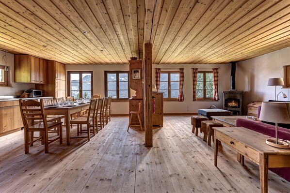 Interior em madeira com área de refeições, cozinha e lareira.