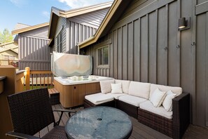 A patio with a hot tub, a wicker sofa, and a round table. - 5BR Park City retreat with hot tub, fireplace, mountain views. (Park City)