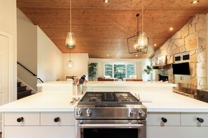 A modern kitchen with a central island, stainless steel appliances, wooden ceiling, and stone wall. - 5BR Park City retreat with hot tub, fireplace, mountain views. (Park City)