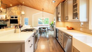 A modern kitchen with wooden ceiling, white cabinetry, and a central island. - 5BR Park City retreat with hot tub, fireplace, mountain views. (Park City)