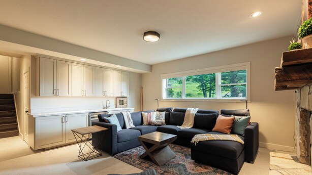 A modern living room with a sectional sofa, a coffee table, and a view of a garden through a window. - 5BR Park City retreat with hot tub, fireplace, mountain views. (Park City)