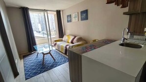A compact living space with a kitchenette, a sofa, a glass table, and a view of the city. - Santa Lucía, Downtown Central Santiago (Santiago)