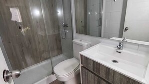 A bathroom with a glass-enclosed shower, a toilet, a sink, and a mirror. - Santa Lucía, Downtown Central Santiago (Santiago)