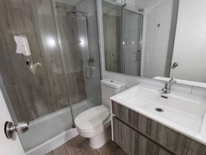 Ein Badezimmer mit Duschkabine, Toilette, Waschbecken und Spiegel.