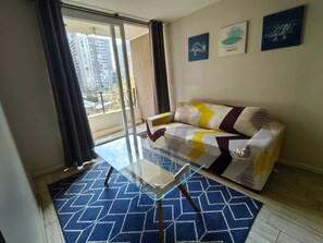 Ein Wohnzimmer mit einer Couch, einem Glastisch und einem gemusterten Teppich.