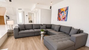 A modern living room with a sectional sofa, a coffee table, and a painting on the wall. - Villa Riviera Luxe, Coastal 4BR Retreat in Miami (Miami)