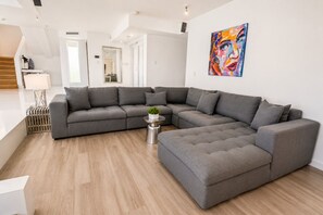 Ein stilvolles Wohnzimmer mit einem Ecksofa, einem Couchtisch und einem Bild an der Wand.