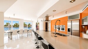A modern kitchen with a large island, stainless steel appliances, and a view of a pool. - Villa Riviera Luxe, Coastal 4BR Retreat in Miami (Miami)