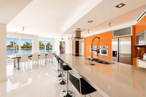 Eine moderne Küche mit einer großen Kochinsel, Edelstahlgeräten und Blick auf einen Pool.