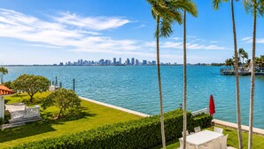 A waterfront property with a view of a city skyline, palm trees, and a pool area. - Villa Riviera Luxe, Coastal 4BR Retreat in Miami (Miami)