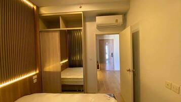 A hotel room with a bed, a walk-in closet, and an air conditioning unit.