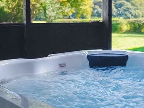 Ein Whirlpool mit Beschriftung, umgeben von einer Holzkonstruktion und Grünpflanzen.