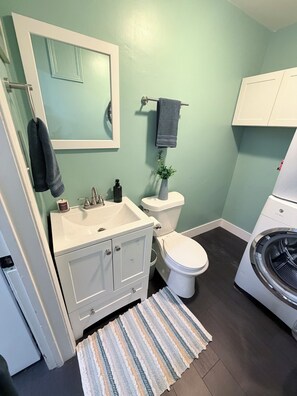 Ein Badezimmer mit weißem Waschbecken, Spiegel, Toilette und Waschmaschine.