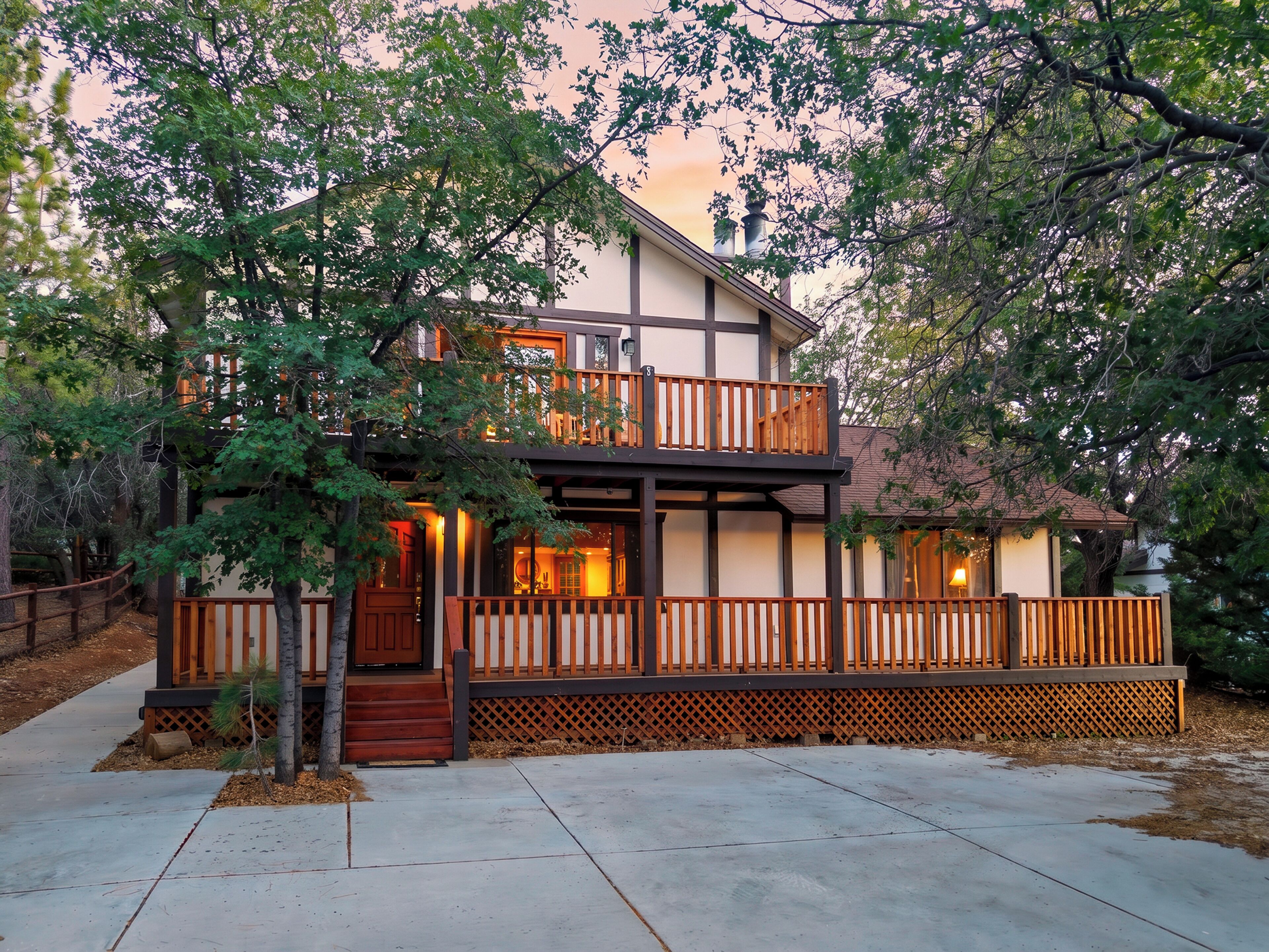 A two-story house with a balcony, wooden deck, and a small front porch.