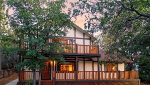 A two-story house with a balcony, wooden deck, and a small front porch. - Vaulted Wood Ceilings + Pine-Shaded Decks | Slopes + Trails | Pinewood Perch (Big Bear)