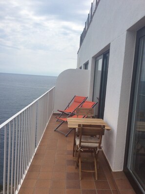 A balcony with a table and chairs, a white railing, and a view of the sea. - CapSaSal Navy: What It's Like to Live on the Bow of a Ship (CT)