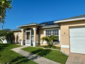 A residential house with a garage, a covered entryway, and a lawn. - 3-bedroom pool house in SW Cape Coral - pet friendly with fenced backyard (Cape Coral)