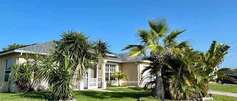 Ett bostadshus med en välskött gräsmatta, palmer och ett garage.