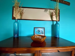 A wooden table with a framed picture of a whale, two blue vases with dried plants, and a wooden bowl. - 3-bedroom pool house in SW Cape Coral - pet friendly with fenced backyard (Cape Coral)
