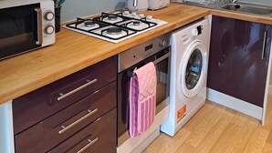 Una cocina compacta equipada con microondas, tostadora, cocina a gas, horno y lavadora.