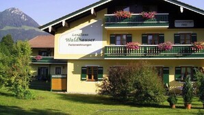 Un edificio de dos pisos con balcones decorados con flores, que dice "Landhaus Waldhauser Ferienwohnungen".