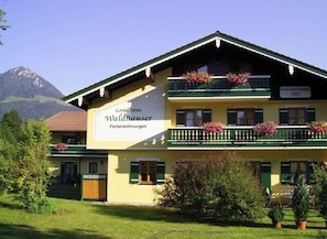 Un immeuble de deux étages doté de balcons ornés de fleurs, portant l’inscription « Landhaus Waldhauser Ferienwohnungen ».