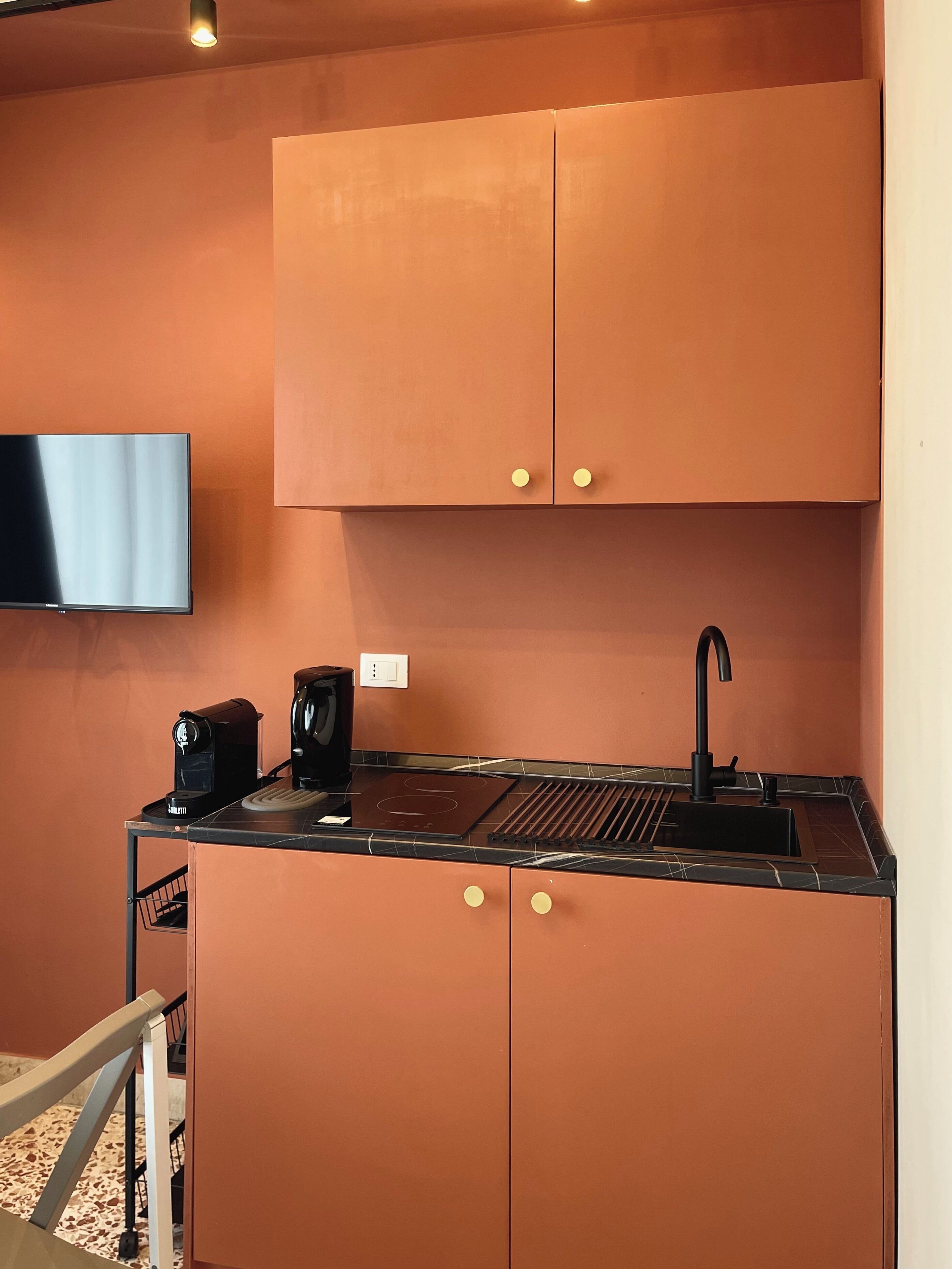 A compact kitchen with a black countertop, a coffee maker, and a sink.