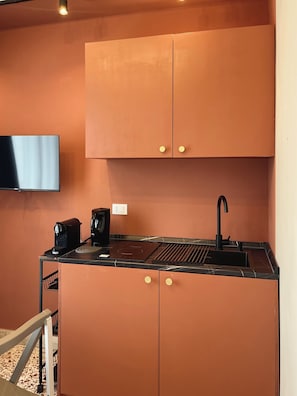 Eine kleine Küche mit schwarzer Arbeitsplatte, einer Kaffeemaschine und einem Spülbecken.