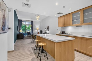 A modern kitchen with a central island, wooden cabinets, and bar stools. - Spacious Designer 1BR in JVC (Dubai)