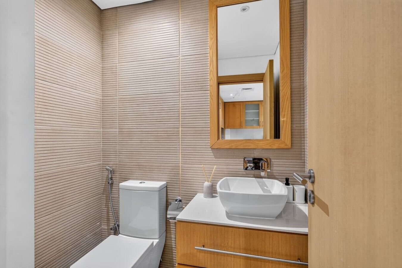 A bathroom with a toilet, bidet, sink, and mirror.