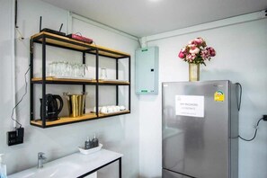 A kitchen with a stainless steel refrigerator, a coffee maker, a sink, and a shelf with glassware and a vase of flowers. - KN Pool Villa Saraburi (Khok Yae)