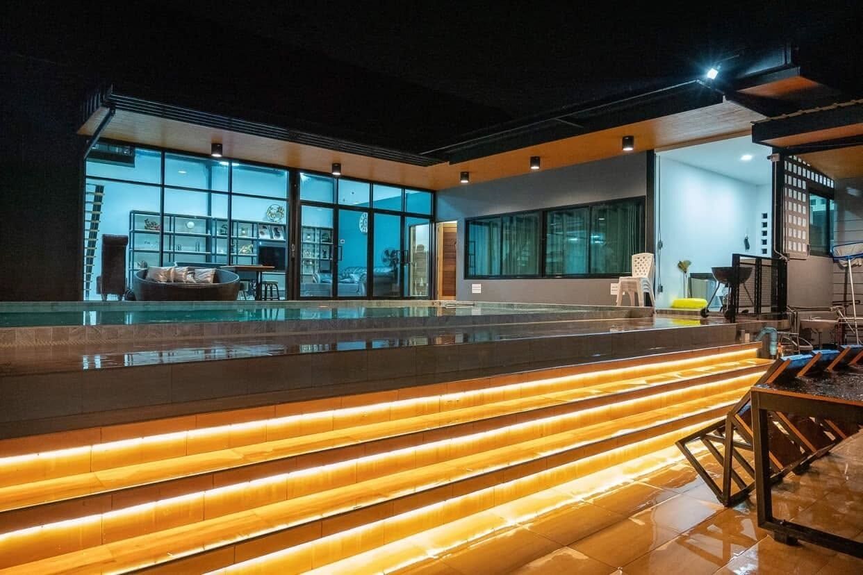 A modern interior with a large glass window, a pool area, and a staircase with illuminated steps.