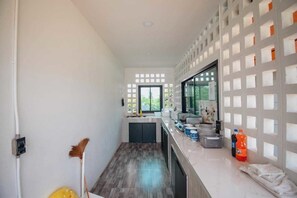 A modern kitchen with a built-in oven, a sink, and a window. - KN Pool Villa Saraburi (Khok Yae)