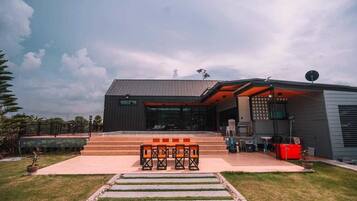 A modern building with a flat roof, large windows, and a patio area with outdoor seating.