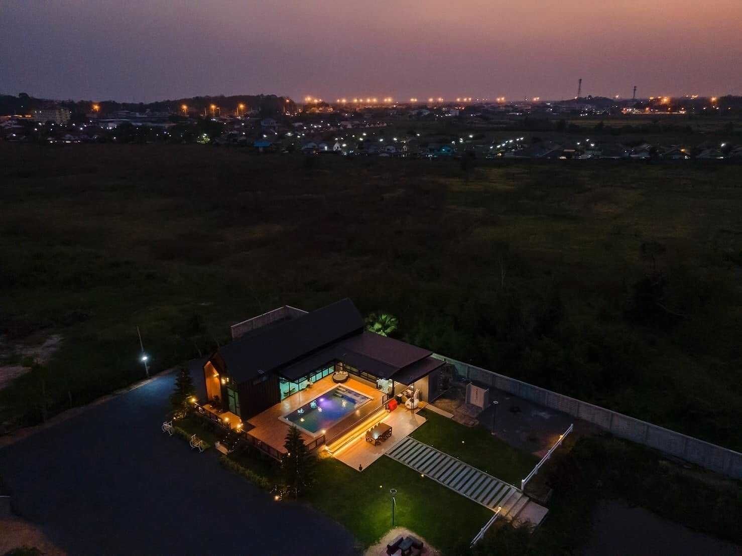 A modern house with a swimming pool, surrounded by a well-maintained lawn and a paved driveway.