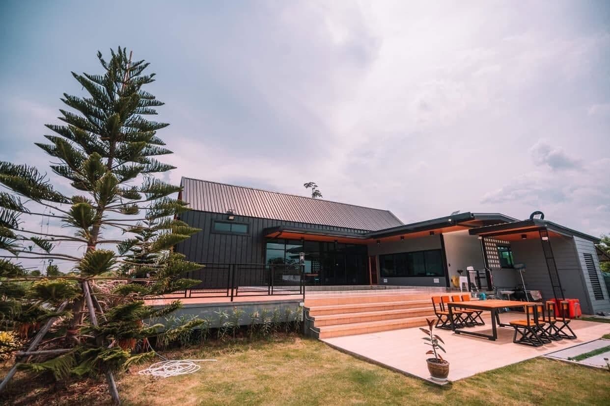 A modern building with a flat roof, large windows, and a covered outdoor seating area with tables and chairs.