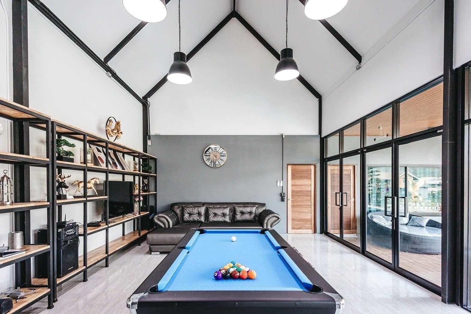 A pool table with balls, a sofa, and shelves with various items.