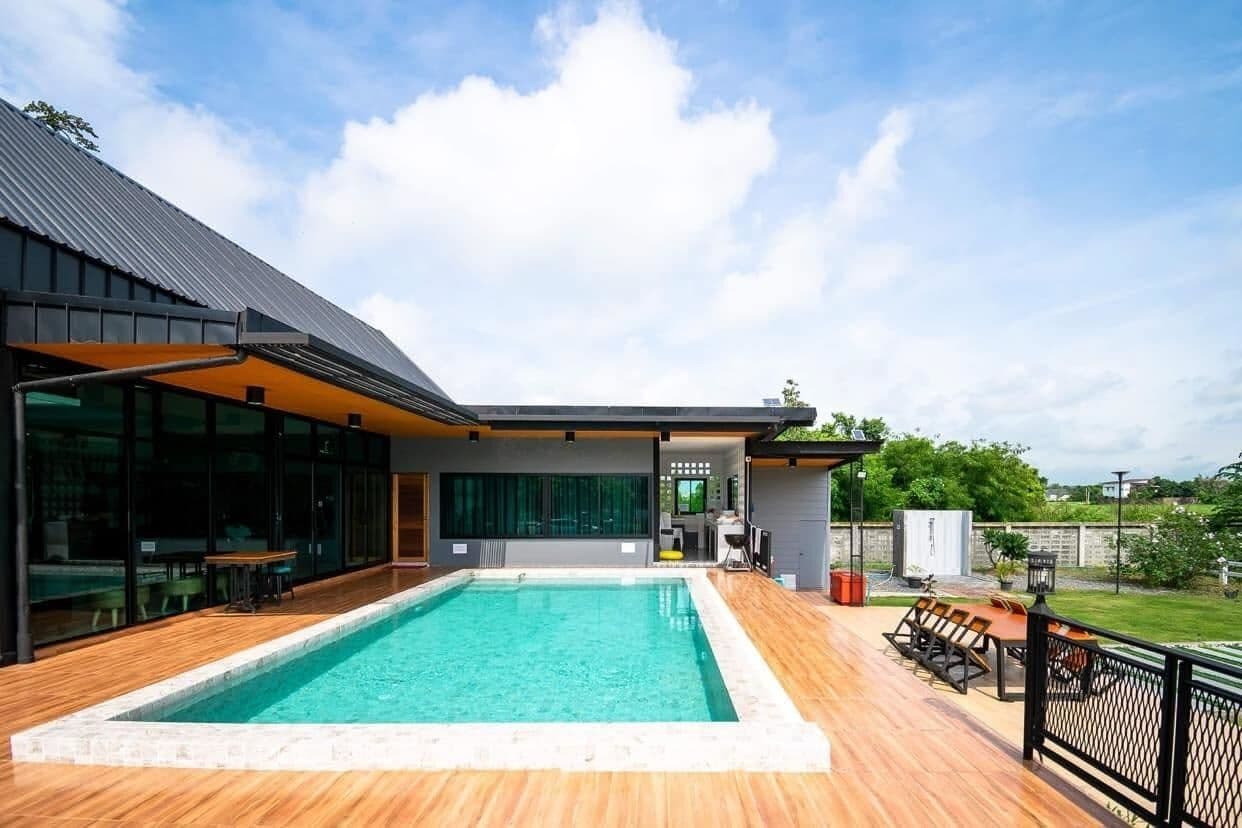 A modern house with a swimming pool, outdoor seating, and a covered patio area.