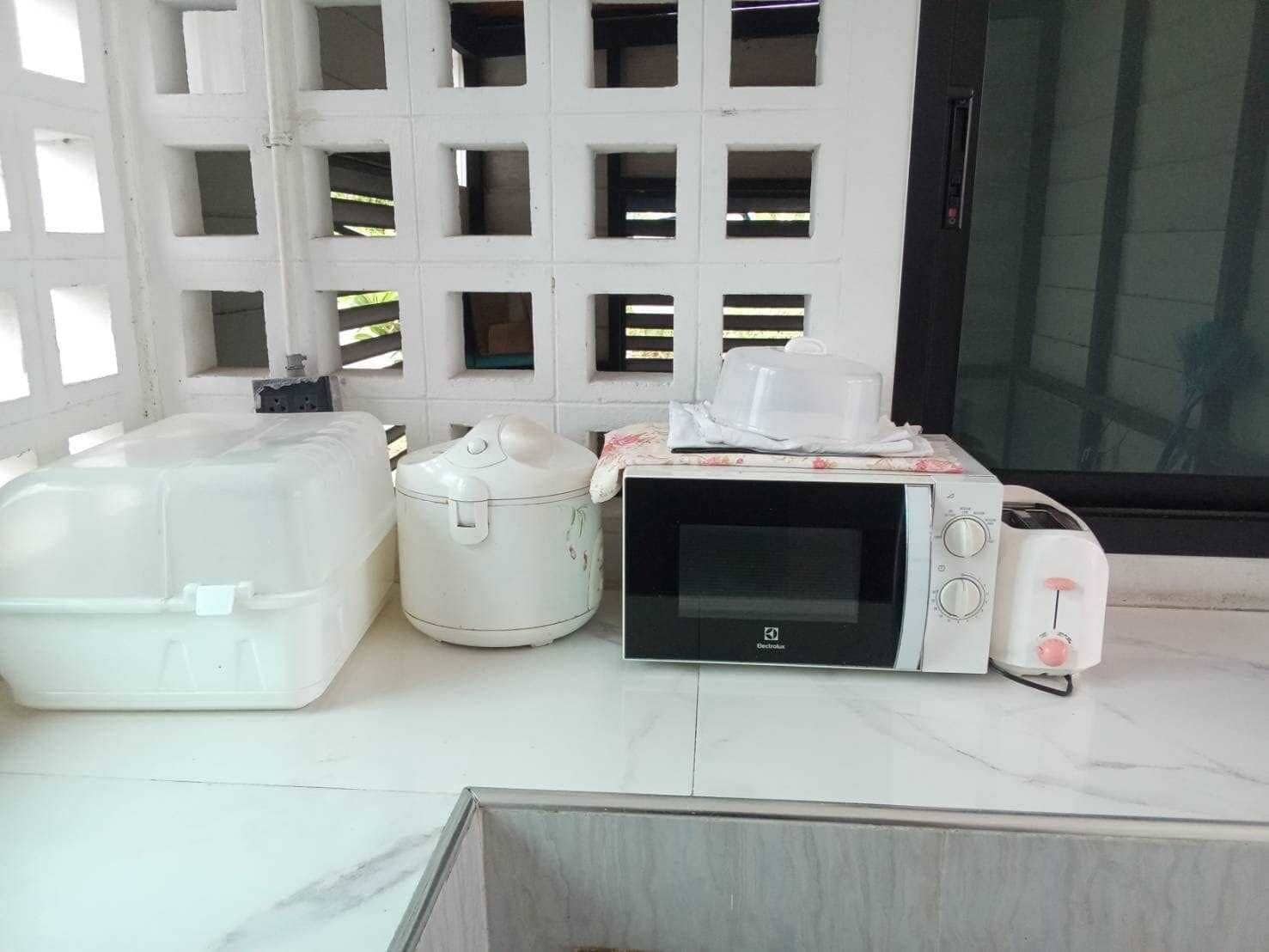 Una cucina con forno a microonde, tostapane e contenitori per alimenti.