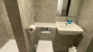 Een badkamer met toilet, wastafel en spiegel.