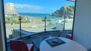 Een balkon met een tafel en stoelen, met uitzicht op een kustgebied onder een heldere lucht.